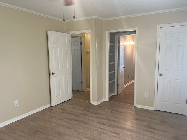 unfurnished bedroom featuring crown molding, wood finished floors, and baseboards