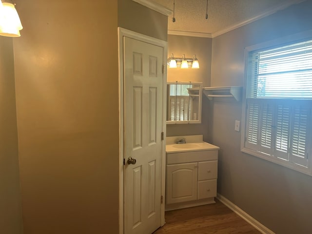 bathroom featuring baseboards, a textured ceiling, crown molding, vanity, and wood finished floors