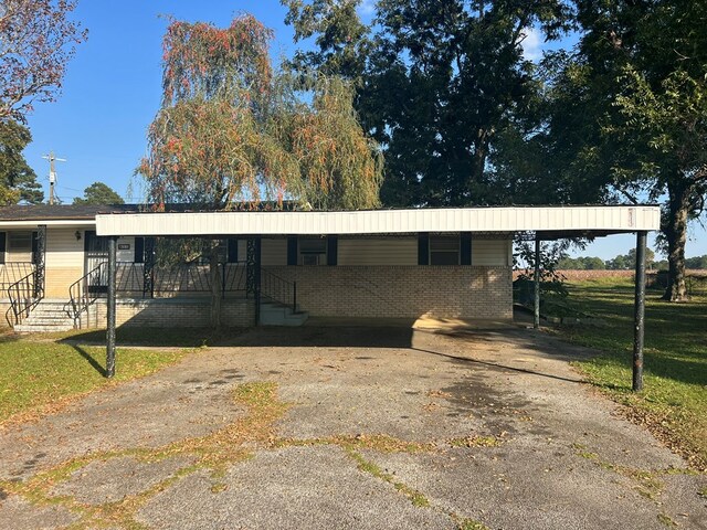 exterior space with a front yard, brick siding, and an attached carport