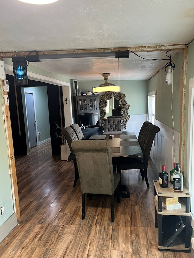 dining area featuring wainscoting, wood finished floors, and a textured ceiling