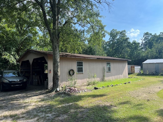 view of home's exterior featuring a yard, a carport, fence, an outbuilding, and driveway