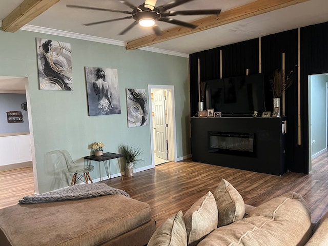 living area with ornamental molding, a fireplace, beam ceiling, ceiling fan, and wood finished floors