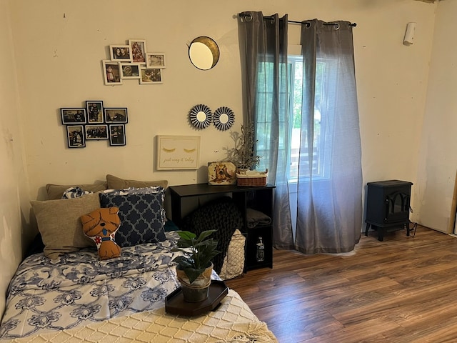 bedroom featuring a wood stove, multiple windows, and wood finished floors