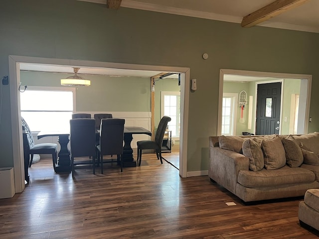 living room with dark wood-type flooring, beamed ceiling, and ornamental molding
