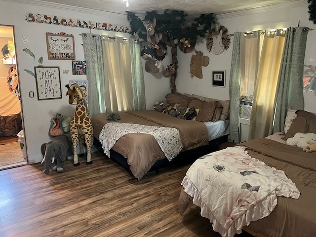 bedroom featuring a textured ceiling, ornamental molding, and wood finished floors