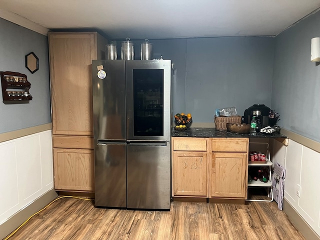 kitchen with wainscoting, wood finished floors, dark countertops, and refrigerator with glass door