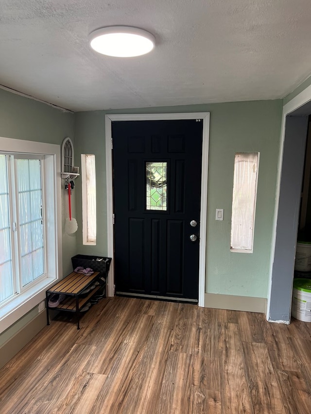 entrance foyer with a textured ceiling, baseboards, and wood finished floors