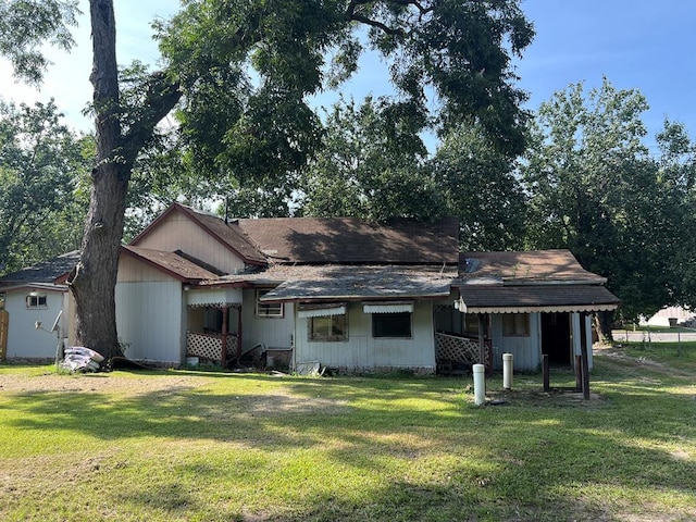rear view of property with a yard and a shingled roof