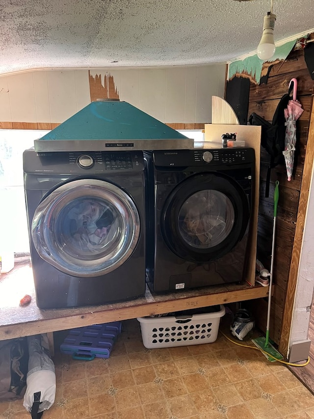 clothes washing area featuring a textured ceiling, washing machine and clothes dryer, and laundry area