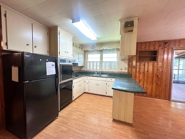 237 Dewey Mcglamry Rd, Fitzgerald, GA 31750 - kitchen featuring black appliances, dark countertops, a peninsula, light wood-type flooring, and wooden walls