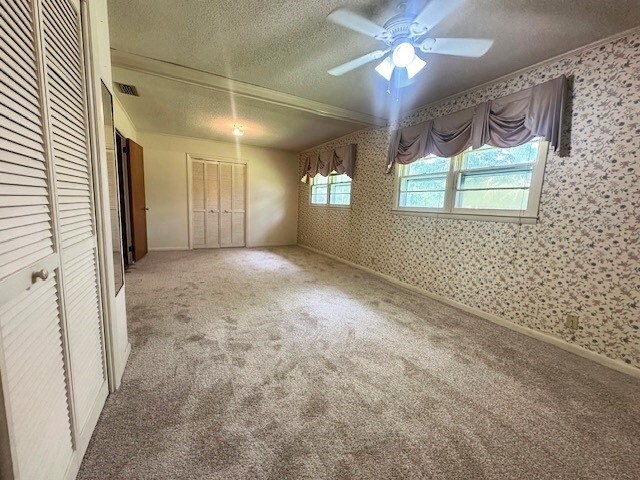 237 Dewey Mcglamry Rd, Fitzgerald, GA 31750 - unfurnished bedroom with a textured ceiling, wallpapered walls, ornamental molding, carpet, and ceiling fan