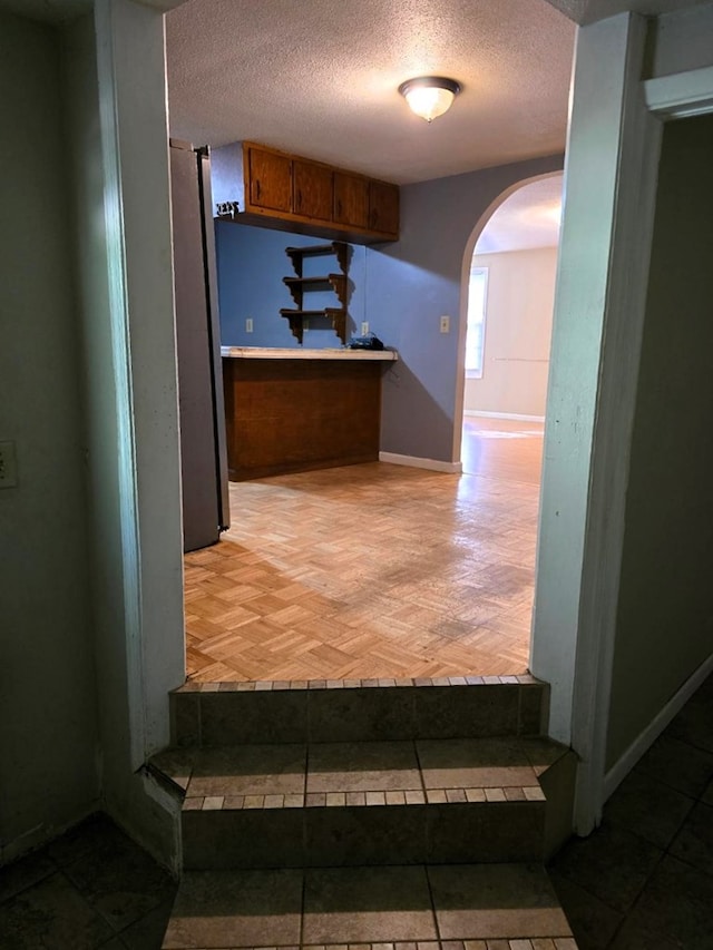 358 Camp Brooklyn Rd, Fitzgerald, GA 31750 - kitchen featuring arched walkways, tile countertops, a textured ceiling, freestanding refrigerator, and brown cabinetry