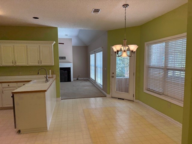 218 Sutton Rd, Tifton, GA 31794 - kitchen with a chandelier, a fireplace, light countertops, lofted ceiling, and decorative light fixtures