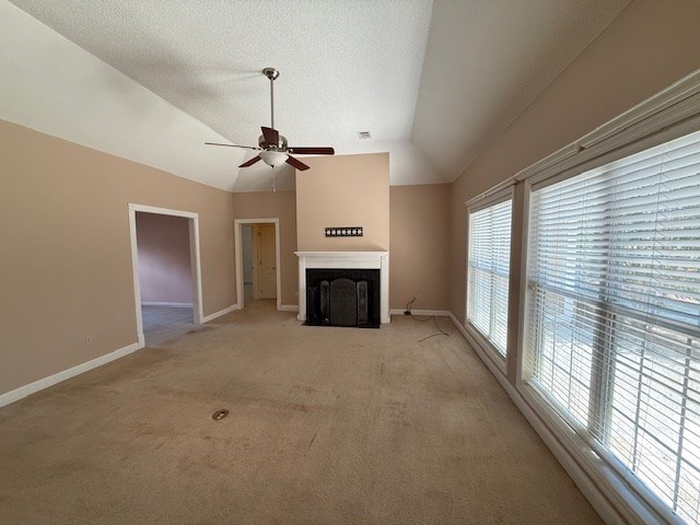 218 Sutton Rd, Tifton, GA 31794 - unfurnished living room with a fireplace with flush hearth, ceiling fan, light carpet, and vaulted ceiling