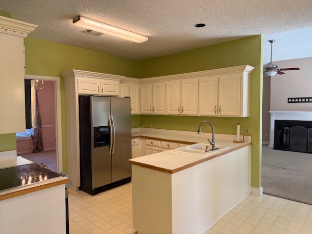 218 Sutton Rd, Tifton, GA 31794 - kitchen featuring stainless steel fridge, light flooring, a ceiling fan, a peninsula, and a textured ceiling