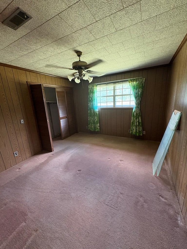 unfurnished bedroom with light colored carpet, wood walls, and visible vents
