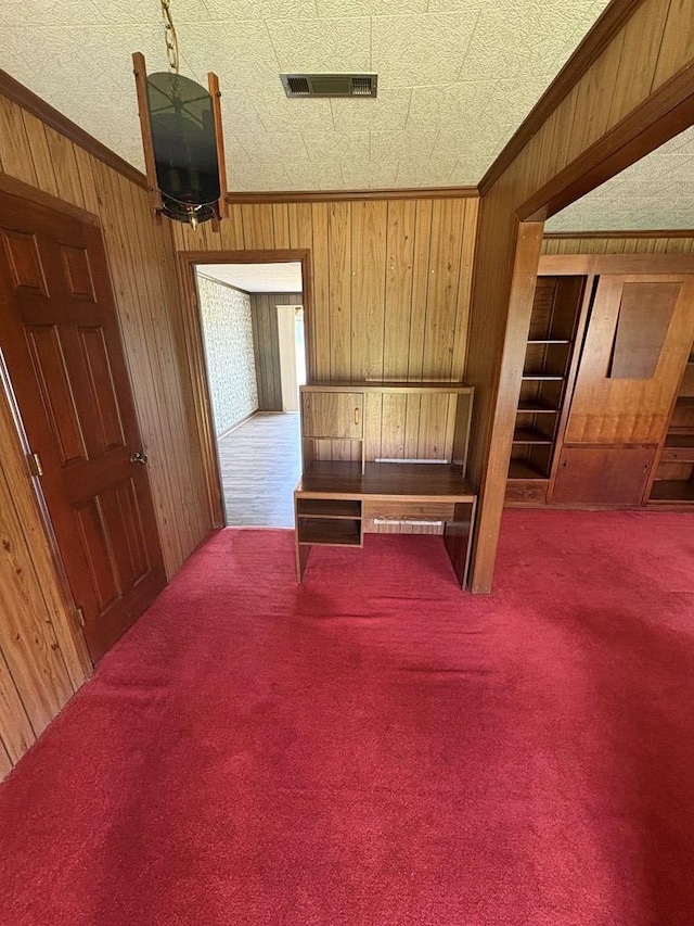 carpeted bedroom featuring crown molding, wood walls, and visible vents