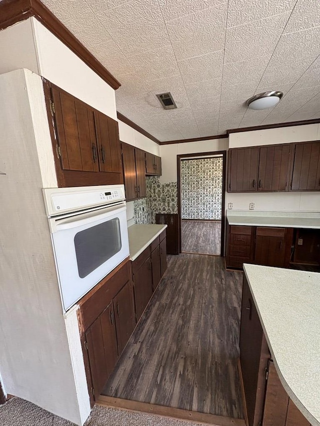 kitchen featuring light countertops, visible vents, white oven, and dark brown cabinets
