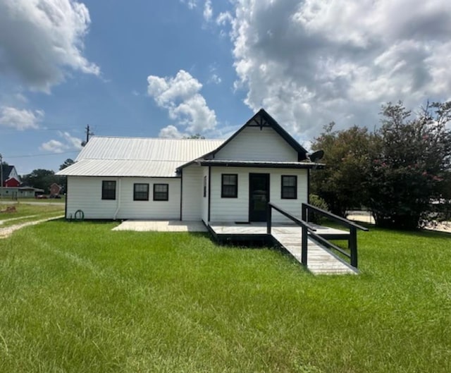 back of house featuring a lawn and metal roof