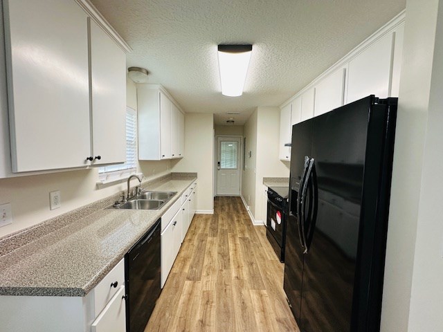 122 Ericas Ct, Fitzgerald, GA 31750 - kitchen with black appliances, light wood-style flooring, white cabinets, and a textured ceiling