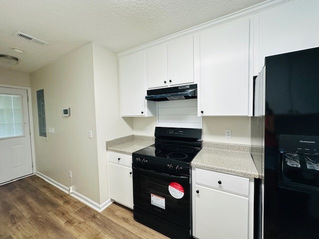 122 Ericas Ct, Fitzgerald, GA 31750 - kitchen featuring black appliances, under cabinet range hood, wood finished floors, white cabinets, and a textured ceiling