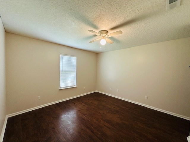 122 Ericas Ct, Fitzgerald, GA 31750 - empty room with dark wood-style flooring, ceiling fan, and a textured ceiling