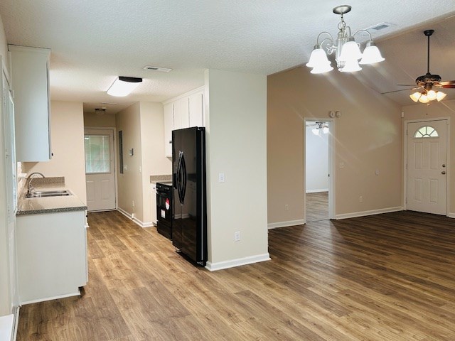 122 Ericas Ct, Fitzgerald, GA 31750 - kitchen featuring freestanding refrigerator, wood finished floors, white cabinets, ceiling fan, and a chandelier