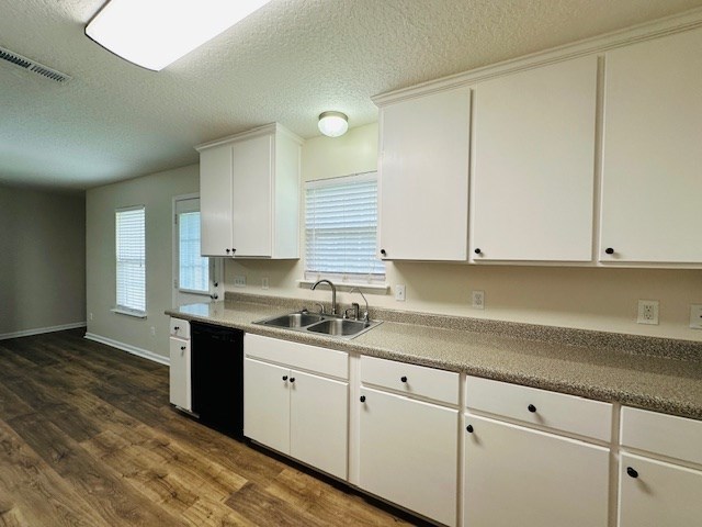 122 Ericas Ct, Fitzgerald, GA 31750 - kitchen with black dishwasher, dark wood finished floors, white cabinetry, and a textured ceiling