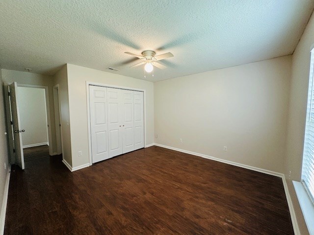 122 Ericas Ct, Fitzgerald, GA 31750 - unfurnished bedroom with wood finished floors, a textured ceiling, a closet, ceiling fan, and multiple windows