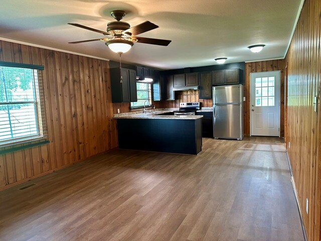 1222 Minton Rd, Sylvester, GA 31791 - kitchen featuring appliances with stainless steel finishes, a peninsula, wood walls, light wood finished floors, and a ceiling fan