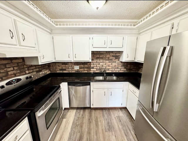311 E 24th St, Tifton, GA 31794 - kitchen featuring white cabinetry, dark countertops, under cabinet range hood, appliances with stainless steel finishes, and a sink