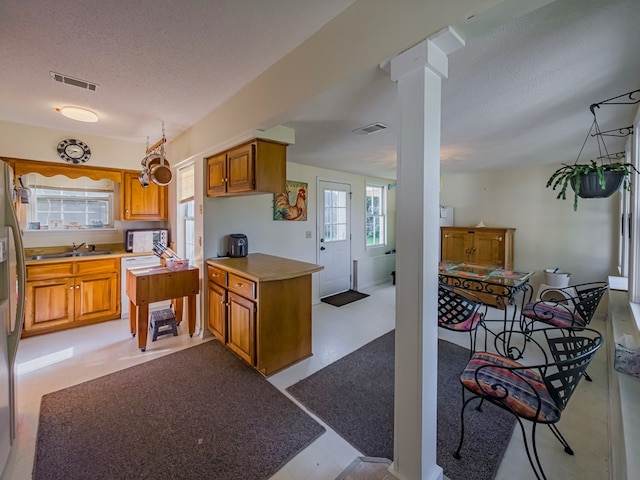 64 Palmetta Rd, Tifton, GA 31794 - kitchen featuring a textured ceiling, brown cabinets, light countertops, and decorative columns