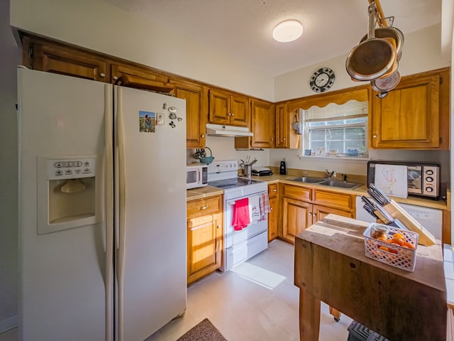 64 Palmetta Rd, Tifton, GA 31794 - kitchen featuring white appliances, under cabinet range hood, light flooring, light countertops, and brown cabinetry