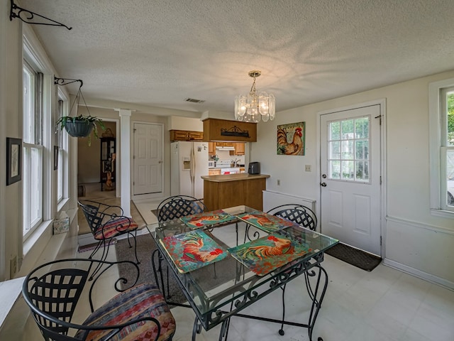 64 Palmetta Rd, Tifton, GA 31794 - dining space with a chandelier, a textured ceiling, ornate columns, and light flooring