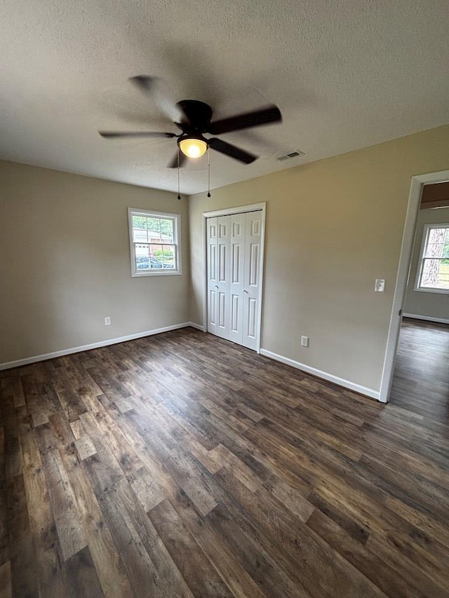 2019 N Central Ave, Tifton, GA 31794 - unfurnished bedroom with dark wood-style flooring, a textured ceiling, multiple windows, baseboards, and a closet