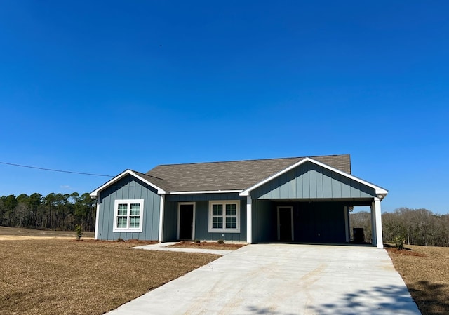 view of front facade with concrete driveway, a carport, and a shingled roof