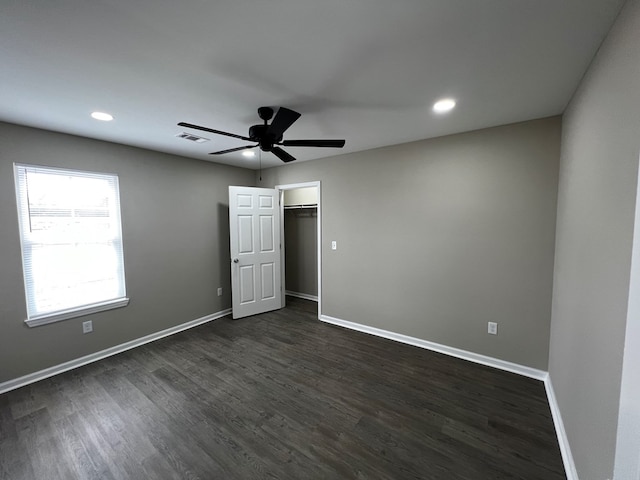 unfurnished bedroom featuring dark wood-type flooring, baseboards, a ceiling fan, and visible vents