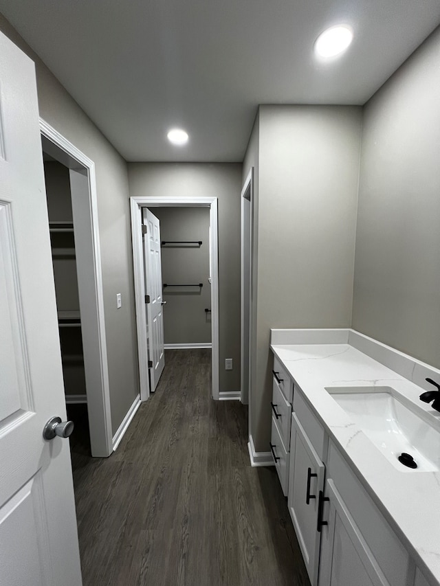 bathroom featuring baseboards, a spacious closet, recessed lighting, vanity, and wood finished floors