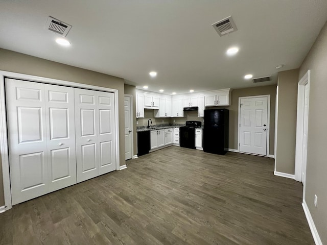 kitchen featuring dark wood-type flooring, visible vents, white cabinetry, and black appliances