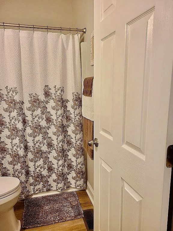 307 E Pinson St, Sylvester, GA 31791 - full bath featuring toilet, curtained shower, and wood finished floors