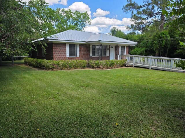105 Gaff Ave, Fitzgerald, GA 31750 - view of front facade featuring metal roof, brick siding, a front lawn, and a deck
