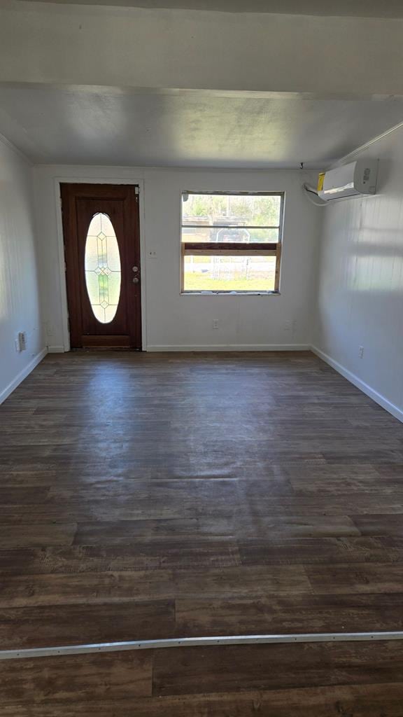 foyer entrance featuring a wall mounted air conditioner, dark wood-type flooring, baseboards, and a healthy amount of sunlight