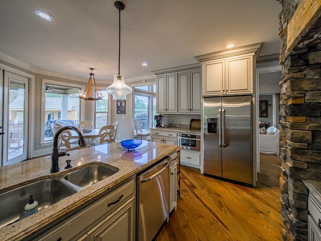 248 Gun Lake Loop, Tifton, GA 31794 - kitchen featuring appliances with stainless steel finishes, wood finished floors, ornamental molding, light stone counters, and decorative light fixtures