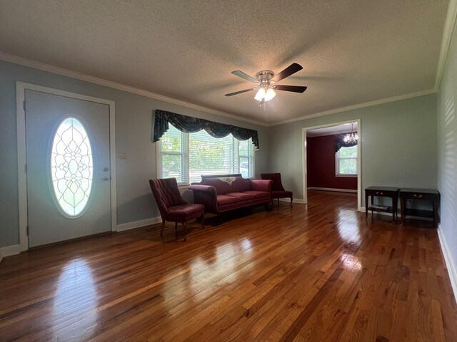entrance foyer with a textured ceiling, wood finished floors, ceiling fan, and crown molding