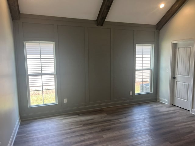 unfurnished room with a decorative wall, dark wood-style flooring, beamed ceiling, and baseboards