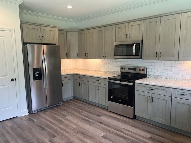 kitchen with stainless steel appliances, recessed lighting, dark wood-type flooring, and ornamental molding