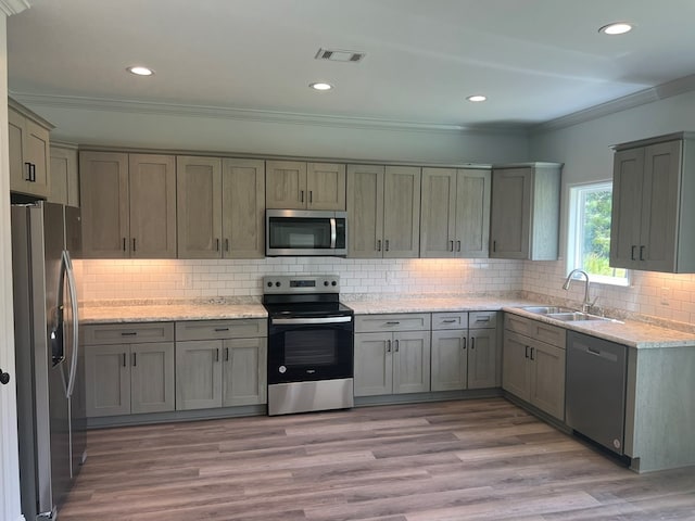 kitchen featuring recessed lighting, stainless steel appliances, ornamental molding, a sink, and tasteful backsplash