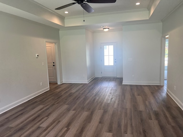 unfurnished room featuring a tray ceiling, baseboards, ceiling fan, crown molding, and dark wood-type flooring