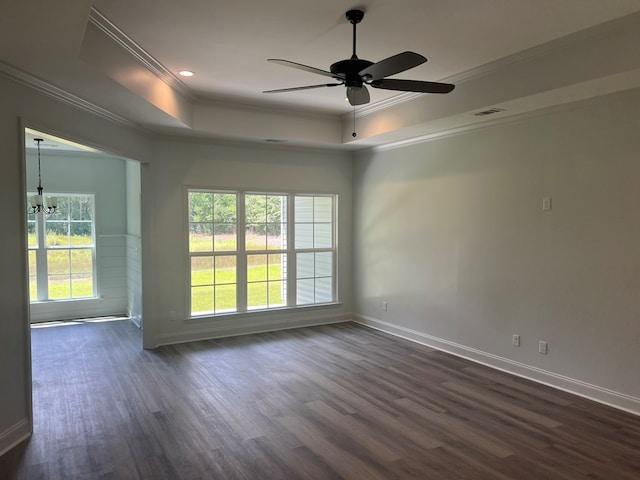 empty room with ceiling fan with notable chandelier, ornamental molding, a tray ceiling, baseboards, and dark wood-style flooring