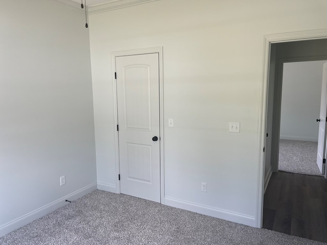 unfurnished bedroom featuring dark colored carpet and baseboards